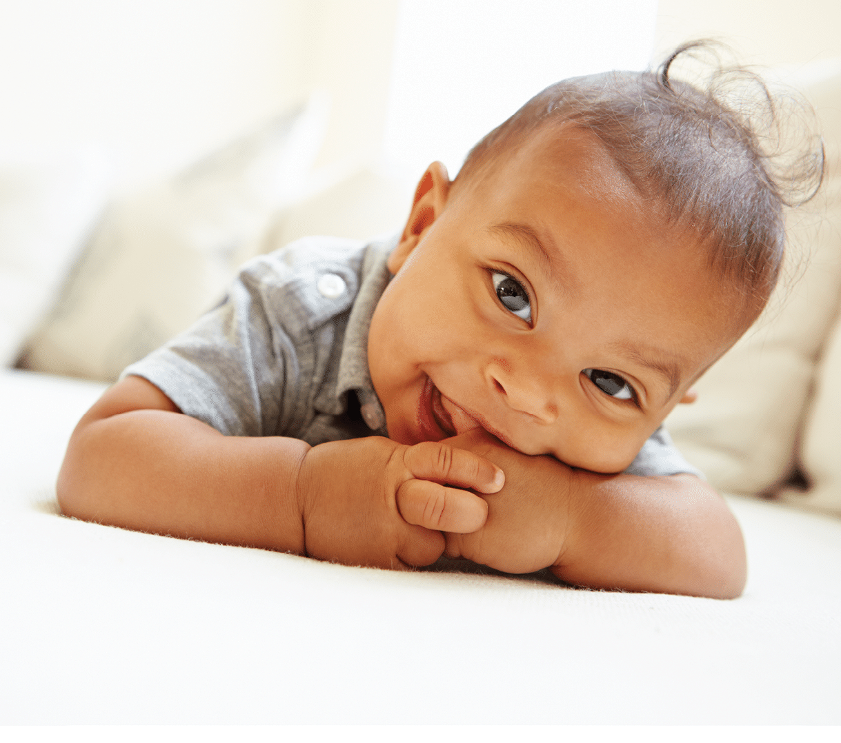 Smiling Baby Boy Lying On Tummy At Home Looking To Camera