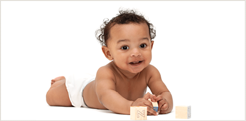 Adorable baby lying on tummy playing with blocks 