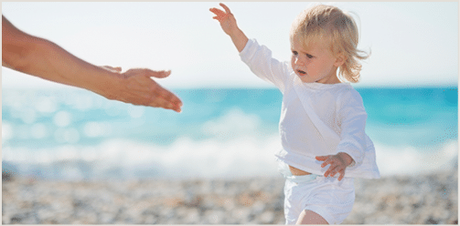 Baby walking to mothers outstretched hands